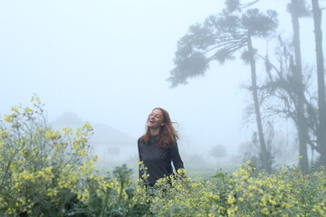 mulher entre flores amarelas em dia de neblina 