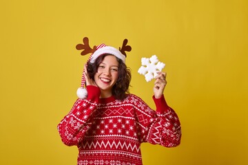 Smiling young woman in a red sweater with a snowflake in her hand.