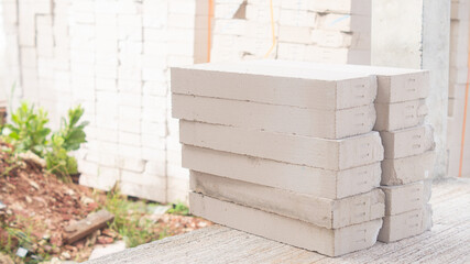 Obraz premium White lightweight bricks stacked in two rows on a cement floor at a construction site. and many more in the background