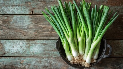 Obraz premium Here's a description for your stock photo, following your specifications.. Fresh green onions in rustic black pot on wooden background.