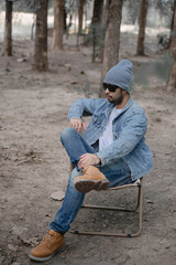 A Stylish Asian Man Wearing a Beanie, Sunglasses, Denim Outfit, and Boots, Exuding Confidence and Modern Fashion, Perfectly Blending Coolness and Elegance in Urban Style