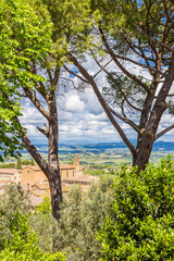 View over the Agostino church between trees in San Gimignano, Italy