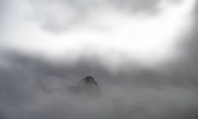 Fotobehang A rocky mountain peak jutting out of the mist and clouds with transparent areas  © Craig Taylor Photo
