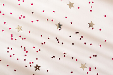 Christmas Holiday Festive Birthday Party composition background. Pink shiny stars on a white surface. Flat lay, top view, copy space. New Year holiday card