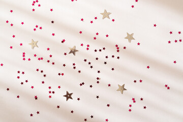 Christmas Holiday Festive composition background. Pink shiny stars on a white surface. Flat lay, top view, copy space. New Year Party holiday card