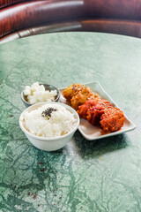 Crispy and Spicy Korean fried chickenon white plate with pickled radish,rice on marble table,Traditional Korean food,Korean foods served on a dining table,The street food of Korea.