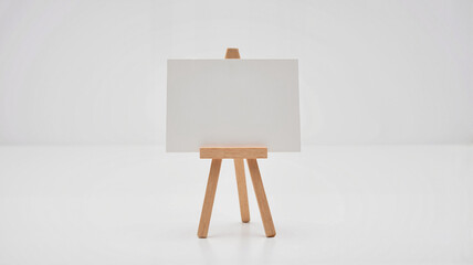 Minimalist wooden easel with blank canvas on white background