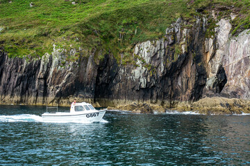 Small Motorboat Navigating Near Rocky Coastal Cliffs