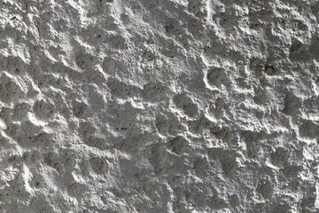 Fototapeta premium A white wall features a rich texture with intriguing patterns and shadows, illuminated by soft natural light.