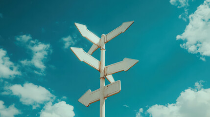 Directional arrows on white signpost against blue sky