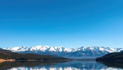 Naklejka premium Serene lake reflecting snow-capped mountains under a clear blue sky.
