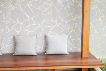 Wooden chair with gray pillows and table in Mediterranean minimal home,scandinavian interior,exterior chair and wooden table in restaurant,warm beige tones,copy space.