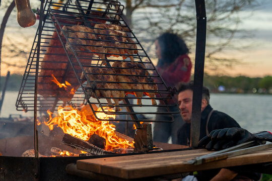 Chefs cooking BBQ and vegetables over open fire in an outdoors setting
