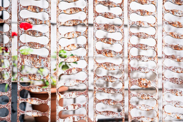 Close-up of aged metal panels with fluid, rhythmic holes, symbolizing the balance between form and function, showcasing the worn beauty of industrial materials in contrast to natural growth