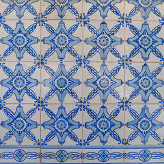 Fragment of building wall with colorful ceramic wall tiles. Azulejo close up. Abstract decorative background, textured ornate pattern for design or backdrop. Traditional ornate Portuguese architecture