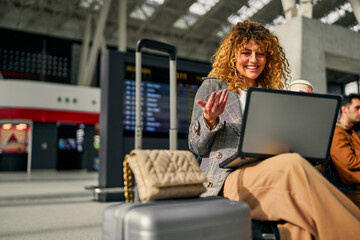 While awaiting the train, a businesswoman participates in an online meeting using her laptop.