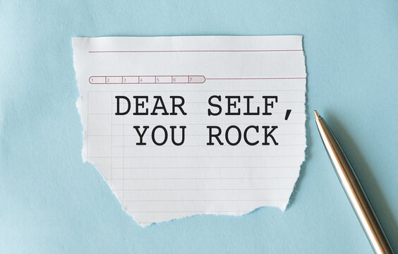 Torn paper on copy space blue background with text DEAR SELF YOU ROCK, concept of positive self talk tor daily affirmation to raise self esteem and self acceptance