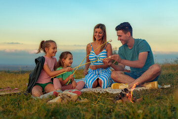 A happy family makes marshmallows by the fire, blended family bounding together. Stepfather...