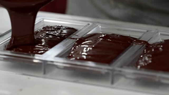 After melting the chocolate, the pastry chef pours it into the molds to make the chocolate bars
