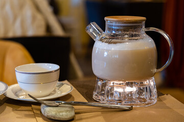 A glass teapot sits on a candle-warmed base, steaming with a comforting beverage in a Moscow cafe. The scene evokes a sense of calm and relaxation.