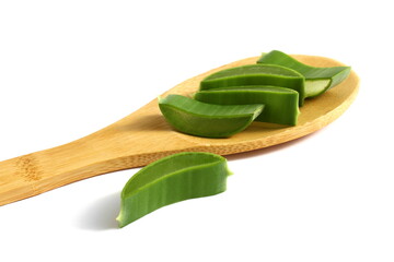 A wooden spoon with aloe leaves lies on a white background.	