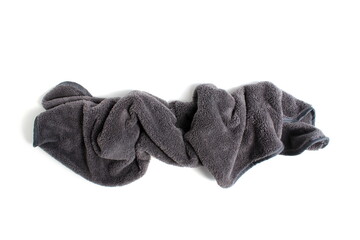 A small grey towel lies crumpled on a white background.	