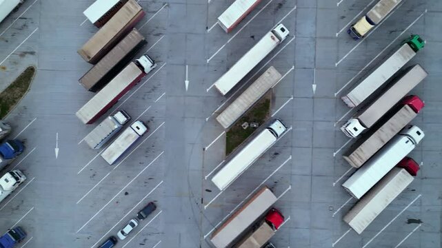 Drone shot of truck parking in Europe seen from above. Aerial footage of rows of vehicles parked for rest at a service station. Neatly placed trucks arranged at a truck stop seen from a helicopter.
