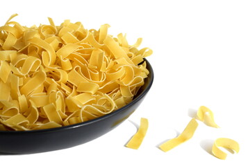 There is a black plate with dry pasta on a white background.