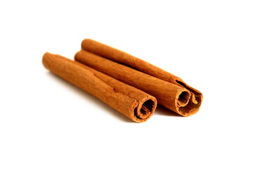 On a white background lie spices, two cinnamon sticks.