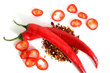 On a white background lies red hot pepper with sliced ​​pieces in a glass bowl.