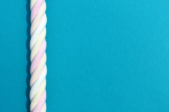 A swirled marshmallow lies on a blue background with space for text.