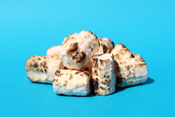 There is a pile of toasted marshmallows on a blue background.