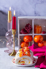 Meringue roll filled with mascarpone, cream and tangerine jam, decorated with tangerines and pomegranate seeds.