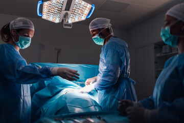 Team of surgeons collaborating during intense operation in operating room - Powered by Adobe