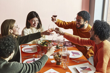 Cheerful friends celebrating Friendsgiving with a festive dinner setting