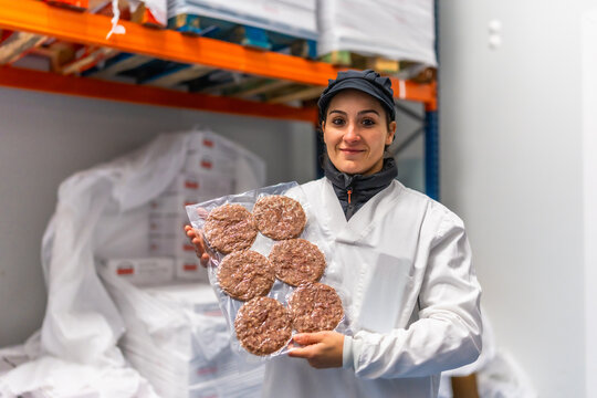 Woman showing packed hamburgers in a meat processing factory