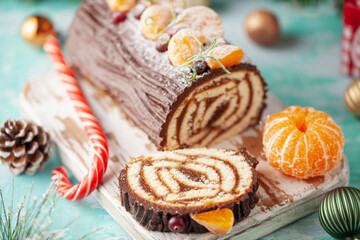 Yule log roll cake with chocolate ganache  on Christmas decorated background
