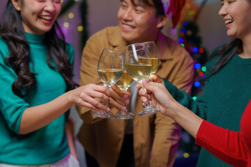 Group of friends toasting with glasses of white wine, enjoying christmas eve together at home