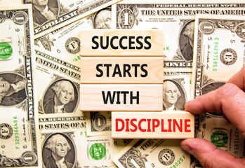 Success starts with discipline symbol. Concept words Success starts with discipline on beautiful wooden blocks. Beautiful dollar background. Business success starts with discipline concept. Copy space © Dzmitry