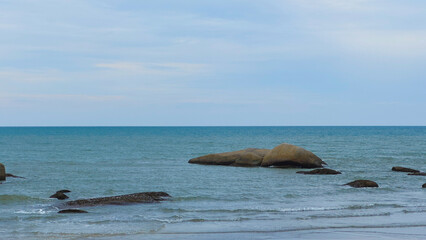 Fototapeta premium Rocky Stones Scattered Across Vast Sea by Beach Shore