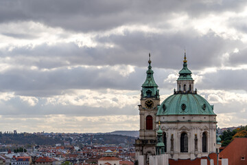 Fototapeta premium Prague's historical architecture, with the St Nicholas' baroque church towers and dome at Mala strana, offering a glimpse into the city's past.