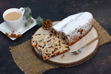 Christstollen auf einer Baumscheibe mit einer Tasse Kaffee. Traditioneller deutscher...