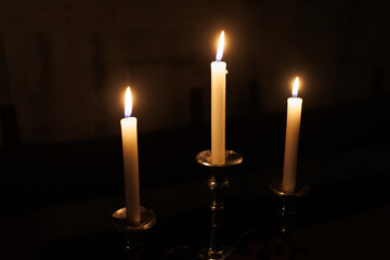 Three glowing candles burning in the dark, creating a serene and tranquil atmosphere