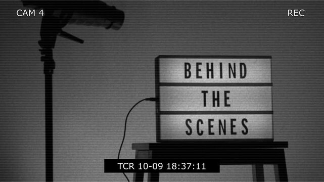 Behind the scene light box in front of vdo camera frame. Black text on white lightbox of word Behind the scenes. Prop for filmmaker movie or film studio. Footage for B roll video production making of.