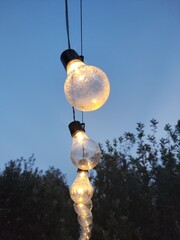 Elegant decorative lamps stand against the backdrop of a serene sky, their intricate designs glowing softly as day transitions into night. A harmonious blend of art, light, and natural beauty.