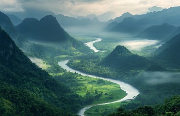 Winding river gracefully flows through dense green mountains under a misty sky at dawn