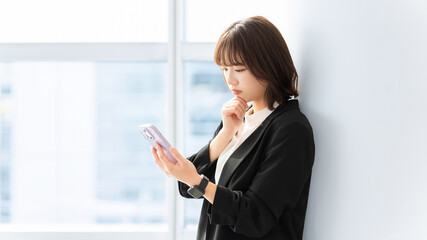 スマホを見て考える女性・ビジネスウーマン