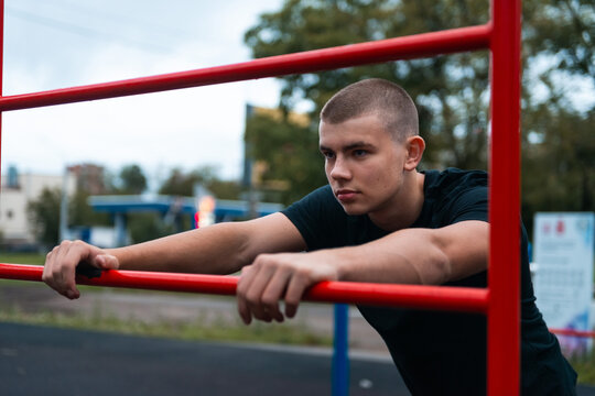 Focused young man exercising on outdoor parallel bars