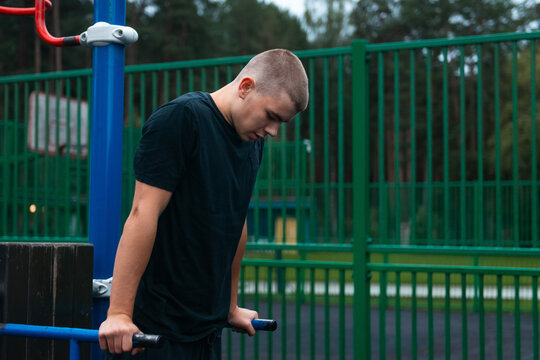 Young man exercising on parallel bars in outdoor park