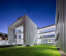 Modern hospital architecture with illuminated facade and garden